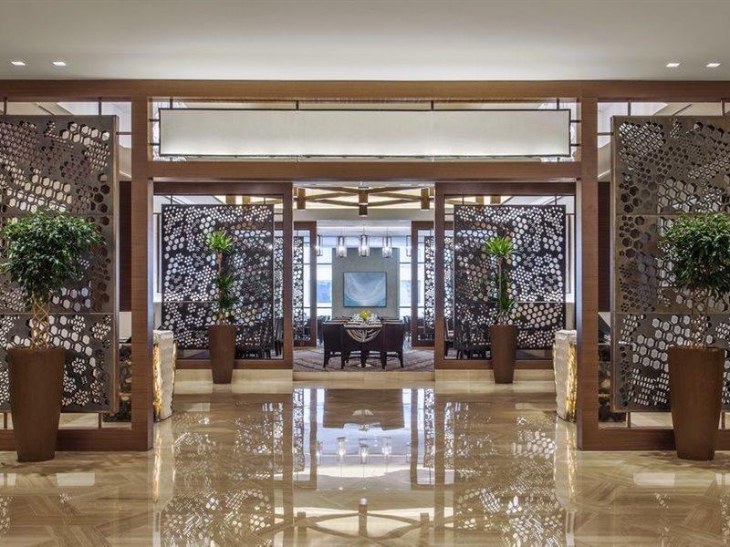 ホテル ジャバール オマール ハイアット リージェンシー マカー メッカ エクステリア 写真 The photo showcases a modern, elegant interior space, likely within a hotel or upscale establishment. It features decorative screens made of intricate patterns that serve as partitions. The floor is polished marble, reflecting the bright lighting abo