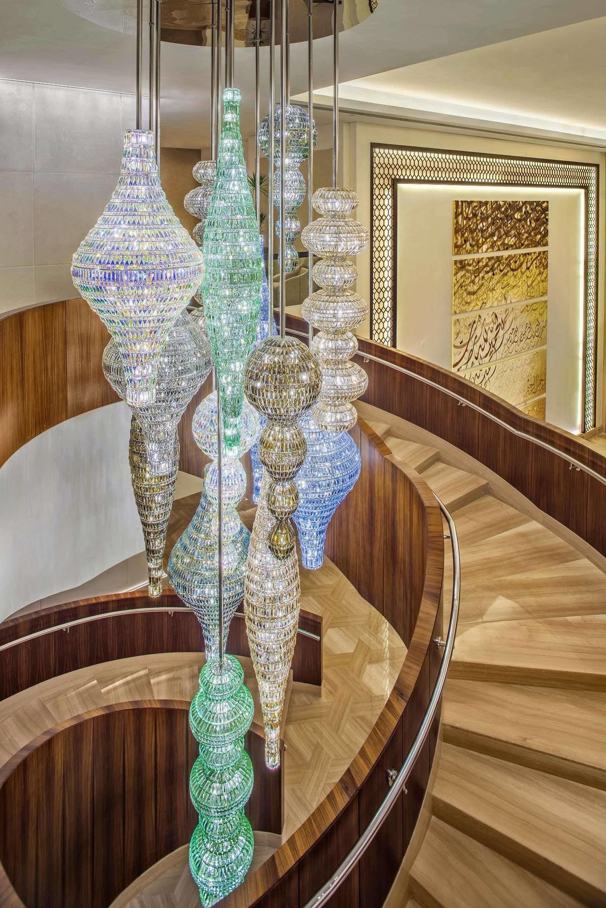 ホテル ジャバール オマール ハイアット リージェンシー マカー メッカ エクステリア 写真 The photo depicts a stylish and elegant interior, showcasing multiple hanging light fixtures, likely made from glass or crystal. These fixtures have intricate designs and vary in shape, resembling elongated forms or vases. They are suspended from the