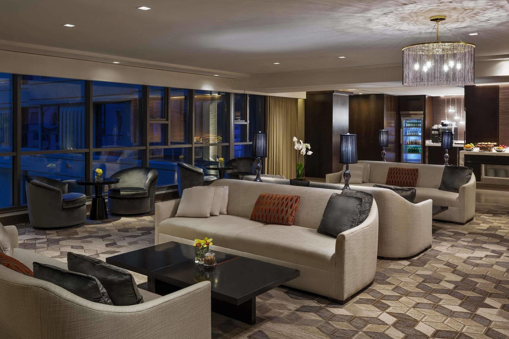 ホテル ジャバール オマール ハイアット リージェンシー マカー メッカ エクステリア 写真 The photo shows a modern and elegant lounge area. It features comfortable cream-colored sofas arranged in a cozy setting, along with dark coffee tables. The space is illuminated by warm lighting, including a stylish chandelier. Large windows allow fo